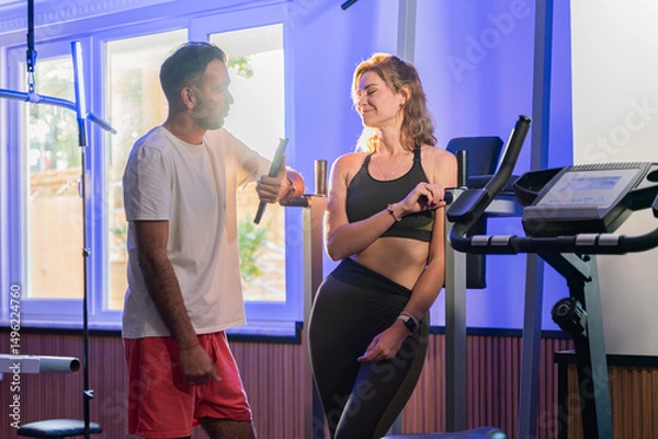 Fototapeta Couple working out in home gym, Personal trainer assisting client