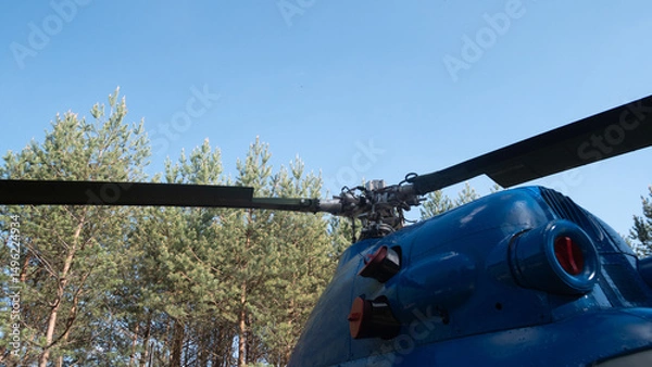 Fototapeta Rotor blades of a vintage Soviet helicopter overlook a lush green forest, highlighting the design and mechanics used in aviation during the USSR era.