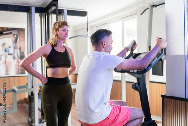 Fototapeta Couple working out in home gym, Personal trainer assisting client