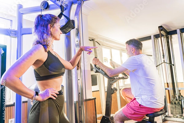 Fototapeta Couple working out in home gym, Personal trainer assisting client