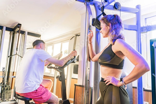 Fototapeta Couple working out in home gym, Personal trainer assisting client