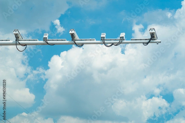 Obraz Traffic surveillance cameras mounted against a clear blue sky with scattered clouds