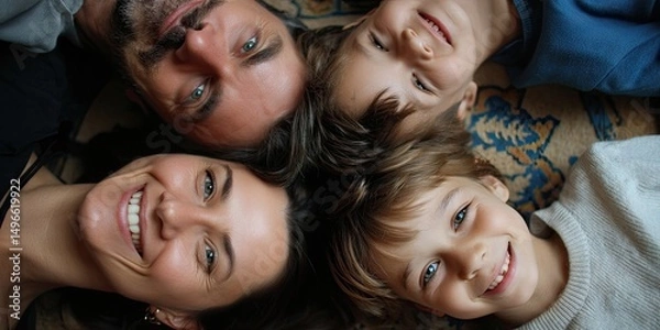 Fototapeta Parents and Kids Lying on Floor, Looking Up. A playful scene where the family lies on the floor, heads together, looking up at the camera with joyful expressions. 