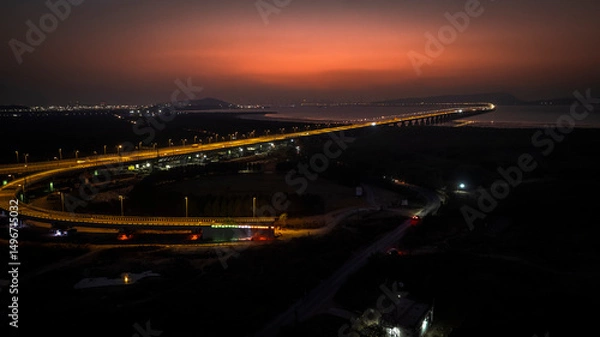 Fototapeta India's longest sea bridge: Trans-Harbour Sea Link. Atal Setu sea bridge in Mumbai, Maharashtra, India. Time-lapse of a city at night with bright skyscrapers and a dense network of glowing buildings.