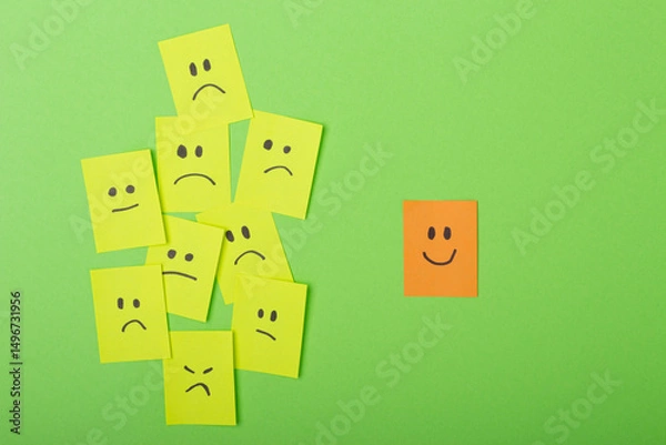 Obraz Positive attitude concept with Colorful Post-Its on Green Surface multiple faces and one standing out with a smile.