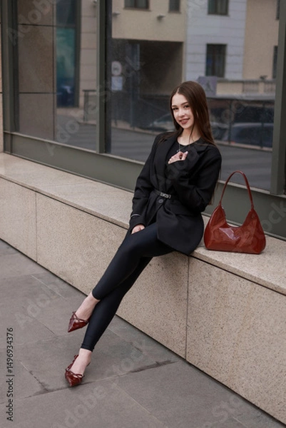 Fototapeta Beautiful girl in patent burgundy shoes against the background of a business center.