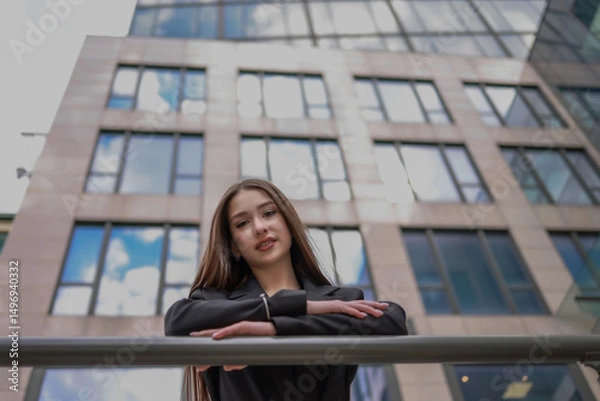 Fototapeta Portrait of a beautiful woman against the background of a modern high-rise building.