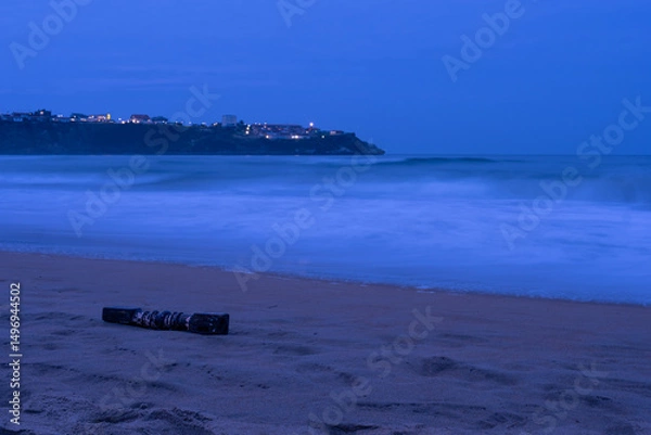 Obraz The beach in teh evening with the lights of the ville on the background