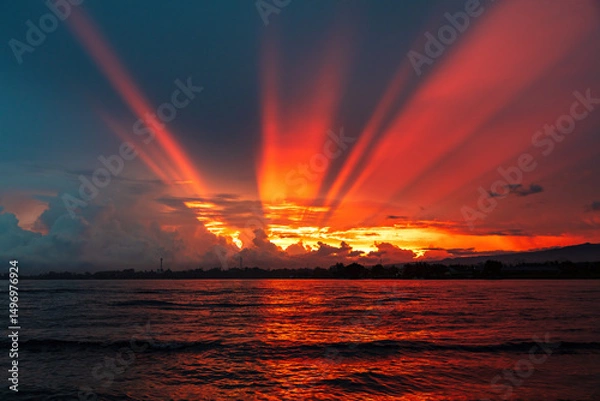 Obraz Brilliant sunrise at Lovina Beach, Bali, Indonesia. Orange rays streaming from the sun behind the clouds. Ocean and reflection of sunbeams in the foreground. 
