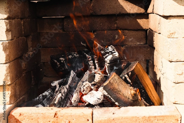 Obraz Fire with flames and embers on a barbecue. Stone barbecue. Burning stone barbecue firewood with fire, open brick oven for cooking food