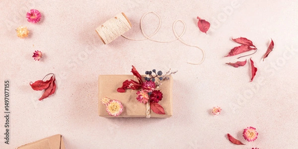 Fototapeta Autumn creative holiday present. Handmade paper gift box with foliage dried leaves on light table. Gift Wrapping. Thanksgiving day, autumn holidays, fall background