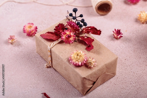 Fototapeta Autumn creative holiday present. Handmade paper gift box with foliage dried leaves on light table. Gift Wrapping. Thanksgiving day, autumn holidays, fall background