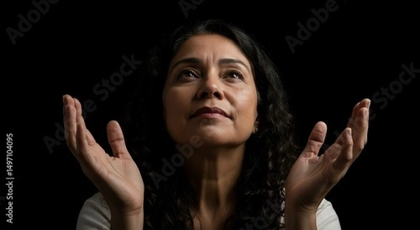 Fototapeta Woman Looking Up with Open Hands in Hopeful Gesture on Black Background