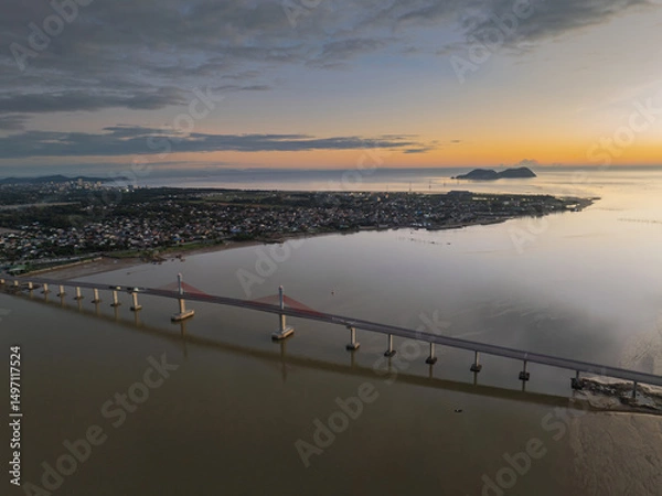 Fototapeta Cua Hoi bridge stretches over Vinh city's river at dusk, showcasing its elegant design and the nearby landscape