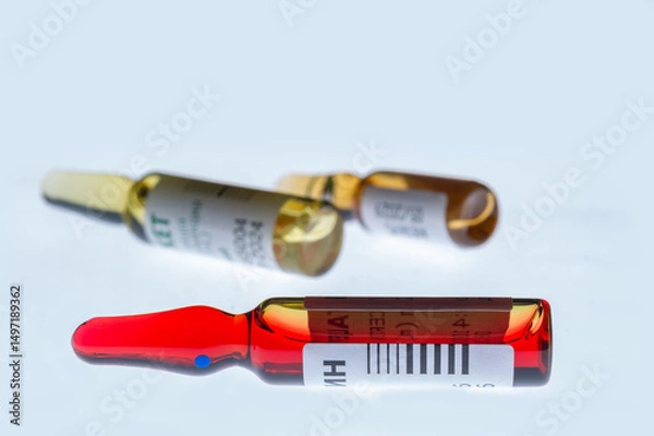 Fototapeta Medical ampoules for injection isolated on a white background. Transparent glass vials with clear liquid used for treatment and vaccination. Sterile pharmaceutical containers in a clinical setting.