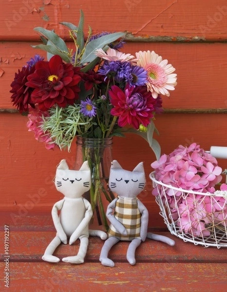 Fototapeta Soft fabric cats sit next to colorful flowers in a rustic setting