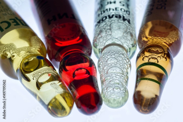 Fototapeta Medical ampoules for injection isolated on a white background. Transparent glass vials with clear liquid used for treatment and vaccination. Sterile pharmaceutical containers in a clinical setting.