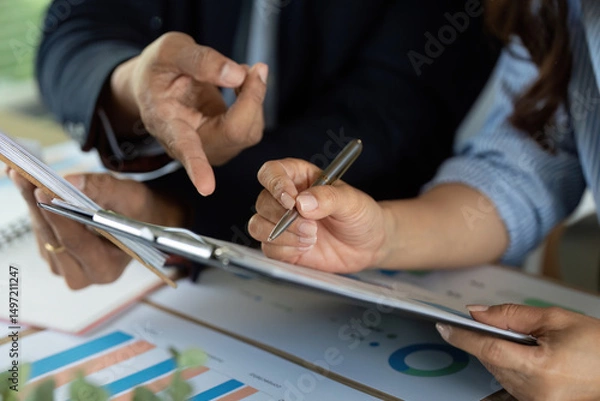 Fototapeta Analyzing Financial Reports. Professionals discussing strategy over charts and documents.