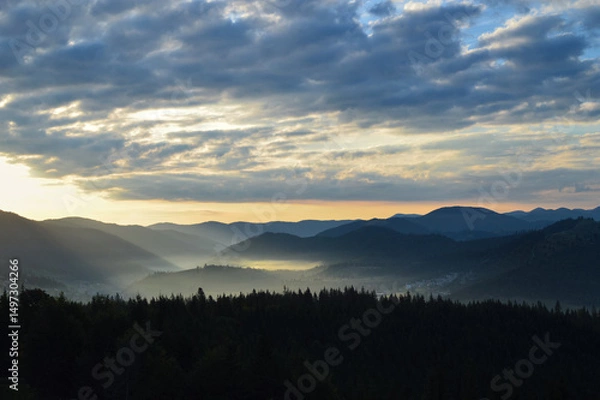 Obraz Sun rising over the Carpathian mountains, panoramic view. Silhouettes of mountain peaks. Morning fog. Dense forest in the foreground.