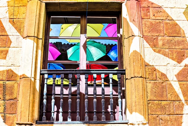 Obraz Set of colorful umbrellas, reflected in the window panes of a building