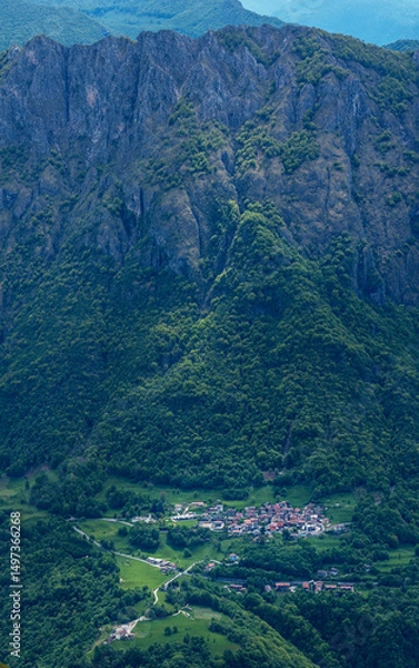 Fototapeta Enchanting vertical view of Parlasco village, nestled storybook-like at the foot of the Pizzi di Parlasco, bathed in magical, soft light that enhances its fairytale charm. Valsassina.