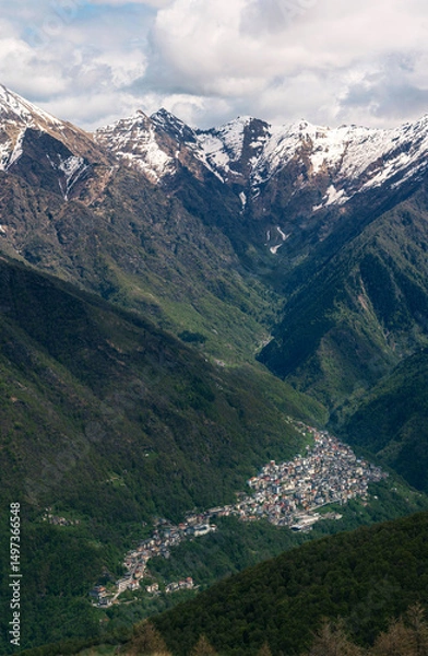 Fototapeta Vertical portrait of the historic village of Premana sprawling up the mountainside, with the imposing Monte Rotondo peak standing sentinel behind, showcasing an iconic Valsassina scene.