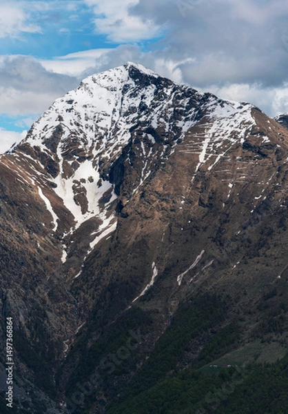 Fototapeta Striking vertical close-up of Monte Legnone's summit, highlighting its sharp, rocky ridges, lingering snowfields, and the intense blue sky of the Italian Alps. Orobie range