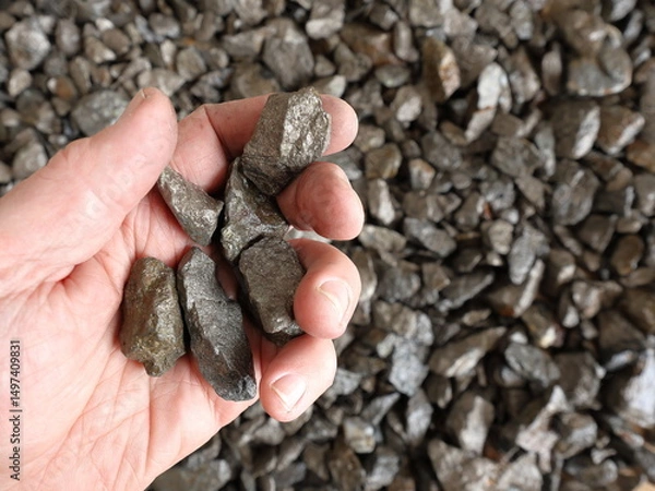 Fototapeta Nickel mine, mining. Hand holding pieces of pentlandite ore. Rocks, textured. Used in alloys such as stainless steel, nickel-cadmium rechargeable batteries, coins