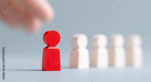 Fototapeta One hand selects a red wooden figure, symbolizing talent selection