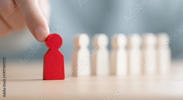 Fototapeta One hand selects a red wooden figure, symbolizing talent selection