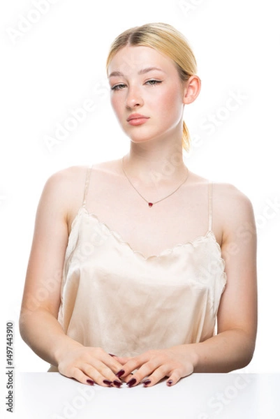 Fototapeta A young blonde girl with freckles in a golden top. Beauty portrait of a woman on a white background in the studio.