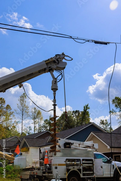 Obraz Heavy machinery is engaged in installation of utility poles surrounded by homes.
