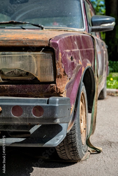 Fototapeta Old rusty vintage car with peeling paint and worn tire on dusty street
