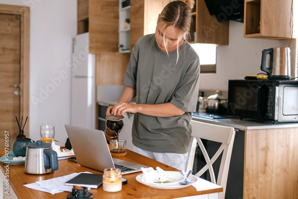 Obraz  Gen Z woman working from home at cozy kitchen table with laptop and phone. Digital nomad lifestyle, mindfulness, remote work, balance, mental calm and modern freelancing