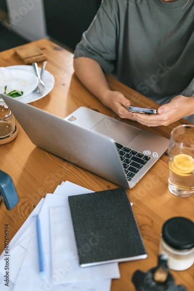Obraz  Gen Z woman working from home at cozy kitchen table with laptop and phone. Digital nomad lifestyle, mindfulness, remote work, balance, mental calm and modern freelancing
