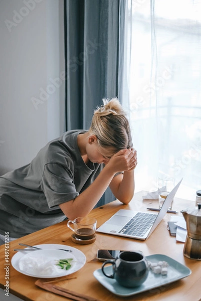 Obraz  Gen Z woman working from home at cozy kitchen table with laptop and phone. Digital nomad lifestyle, mindfulness, remote work, balance, mental calm and modern freelancing
