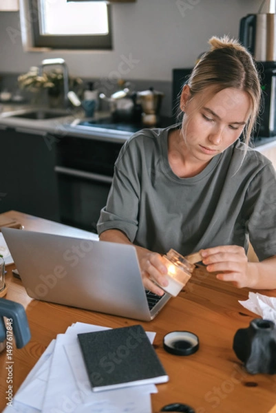 Obraz  Gen Z woman working from home at cozy kitchen table with laptop and phone. Digital nomad lifestyle, mindfulness, remote work, balance, mental calm and modern freelancing