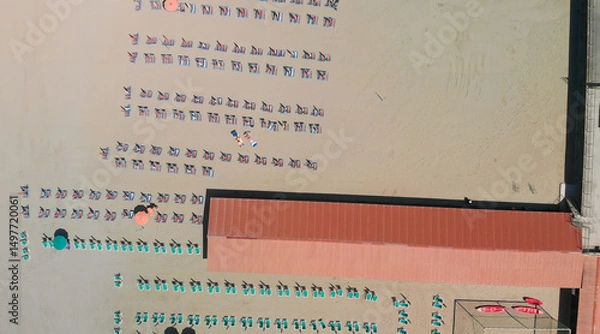 Fototapeta Aerial drone view of a seaside beach resort with colorful umbrellas and summer vacation atmosphere