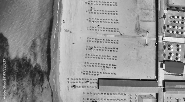 Fototapeta Aerial top-down view of a seaside beach resort with rows of umbrellas and sunbeds in summer