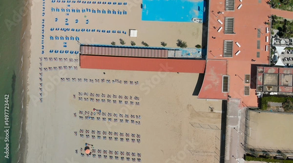 Fototapeta Aerial top-down view of a seaside beach resort with rows of umbrellas and sunbeds in summer