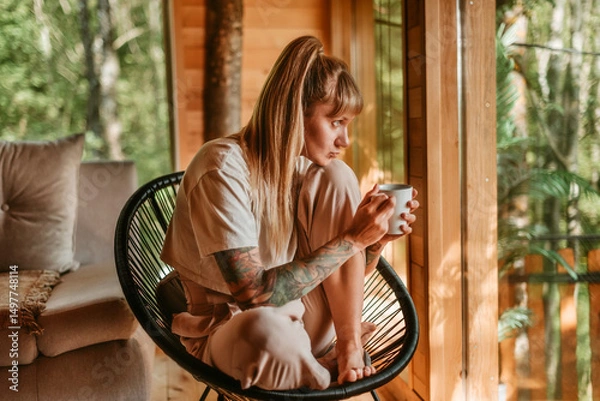 Fototapeta Woman Enjoying Drink in Cozy Forest Cabin