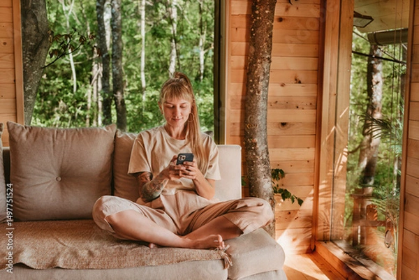 Fototapeta Woman Using Smart Phone in Log Cabin