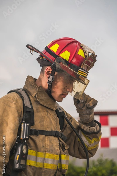 Fototapeta Brave firefighter of Egyptian origin putting on and adjusting his helmet, ready to go put out a fire.
