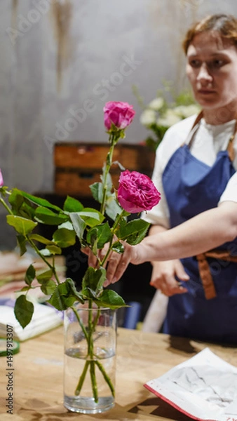 Fototapeta A florist makes a bouquet of pink roses in a flower shop. Small business.  Close-Up.