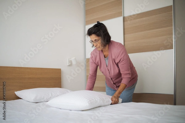 Fototapeta The host gently adjusts each pillow for a warm, inviting feel
