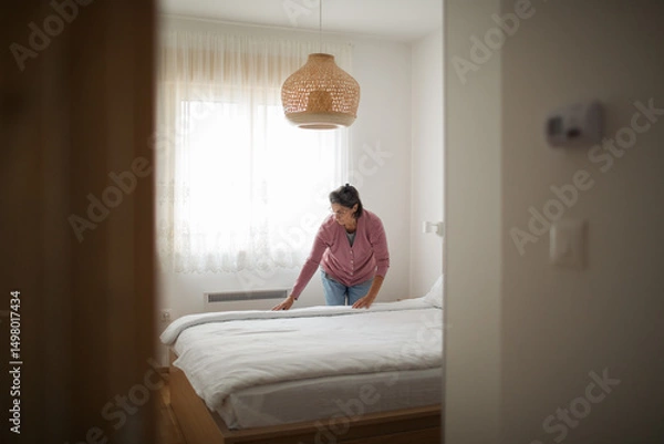 Fototapeta Warm-hearted host prepares the room for her next guest with care