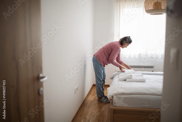 Fototapeta Seasoned host sets the bed with quiet dedication and warmth