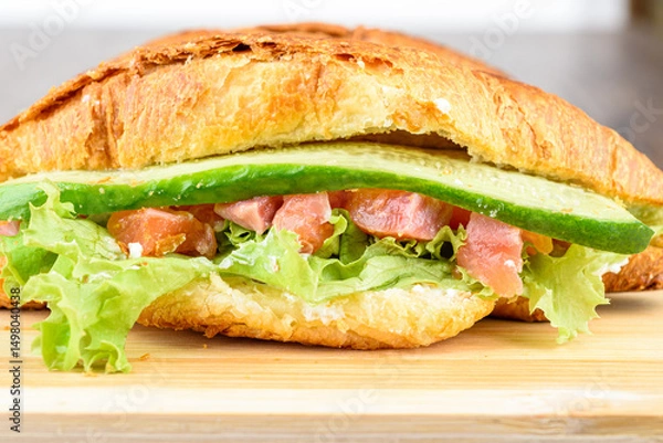 Obraz Close-up of croissant with lettuce, soft cheese and red fish with cucumber filling.