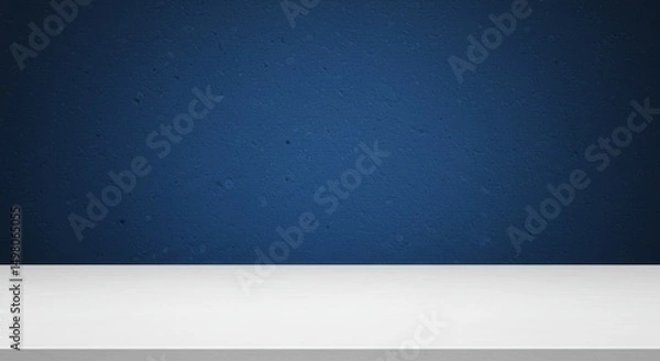 Obraz Blue Wall White Tabletop Background - Clean white tabletop against a textured dark blue wall background. Perfect for product displays or presentations