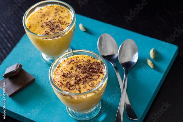 Obraz Mango lassi is a popular Indian refreshing healthy drink made of mango, yogurt and cardamom, decorated with chocolate. On a turquoise wooden background